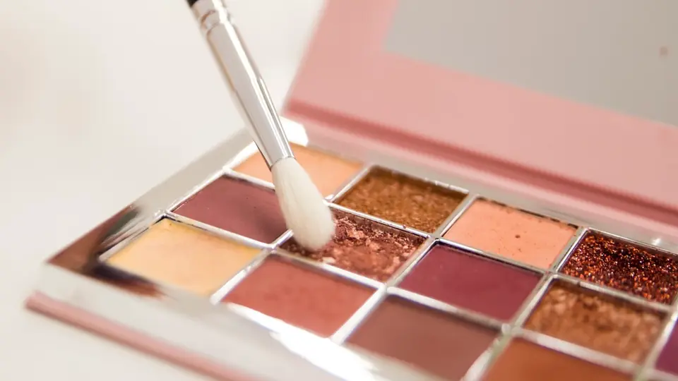 Pincel sobre una paleta de sombras en tonos cálidos